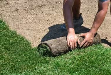 Een hovenier legt graszodes neer voor de tuinaanleg.